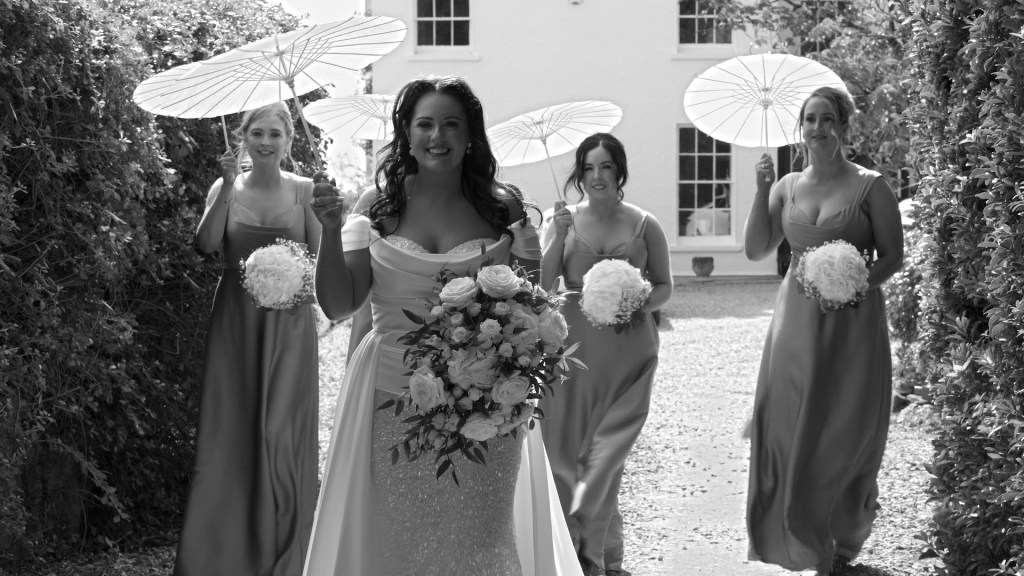 Bride Gemma and bridesmaids holding white umbrellas and flower bouquets at a private house near Greencastle.