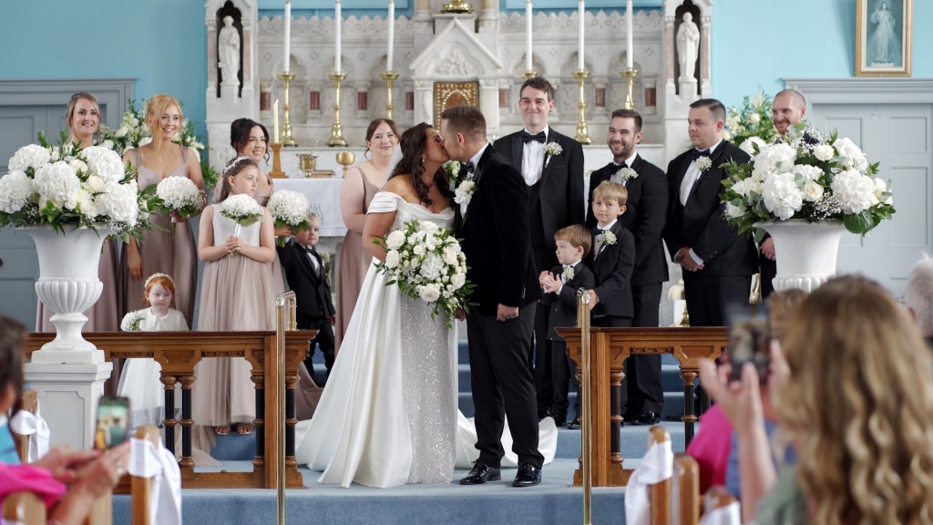 Gemma and Josh's first kiss at the altar of St Mary’s Church, Ballybrack, surrounded by their wedding party.