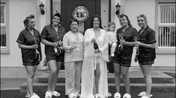 Black and white video of bride Charlene popping a champagne bottle with her bridesmaids and a child during wedding morning preparations.