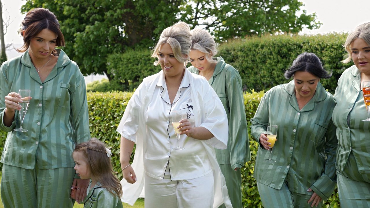 A joyful morning scene of Bride Ciara and her bridesmaids wearing coordinating white and sage green pyjamas.