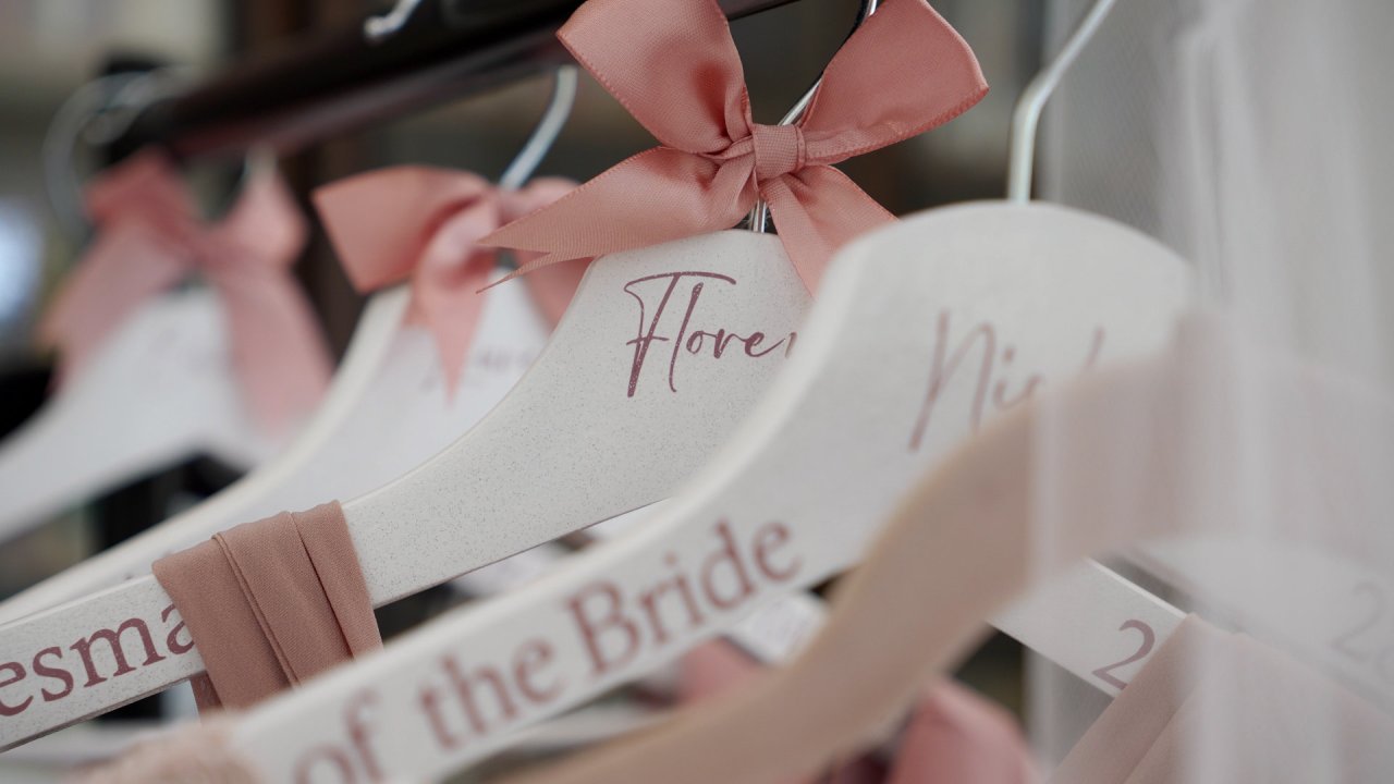 Custom white wooden clothes hangers with pink bows for the bridesmaids at a Beech Hill wedding.