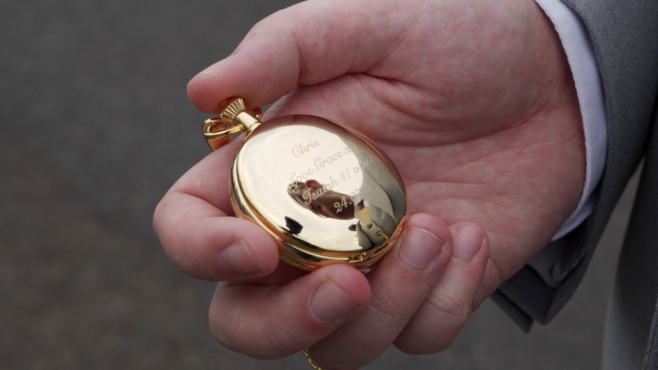 A detailed macro shot of a polished gold pocket watch held in a hand.