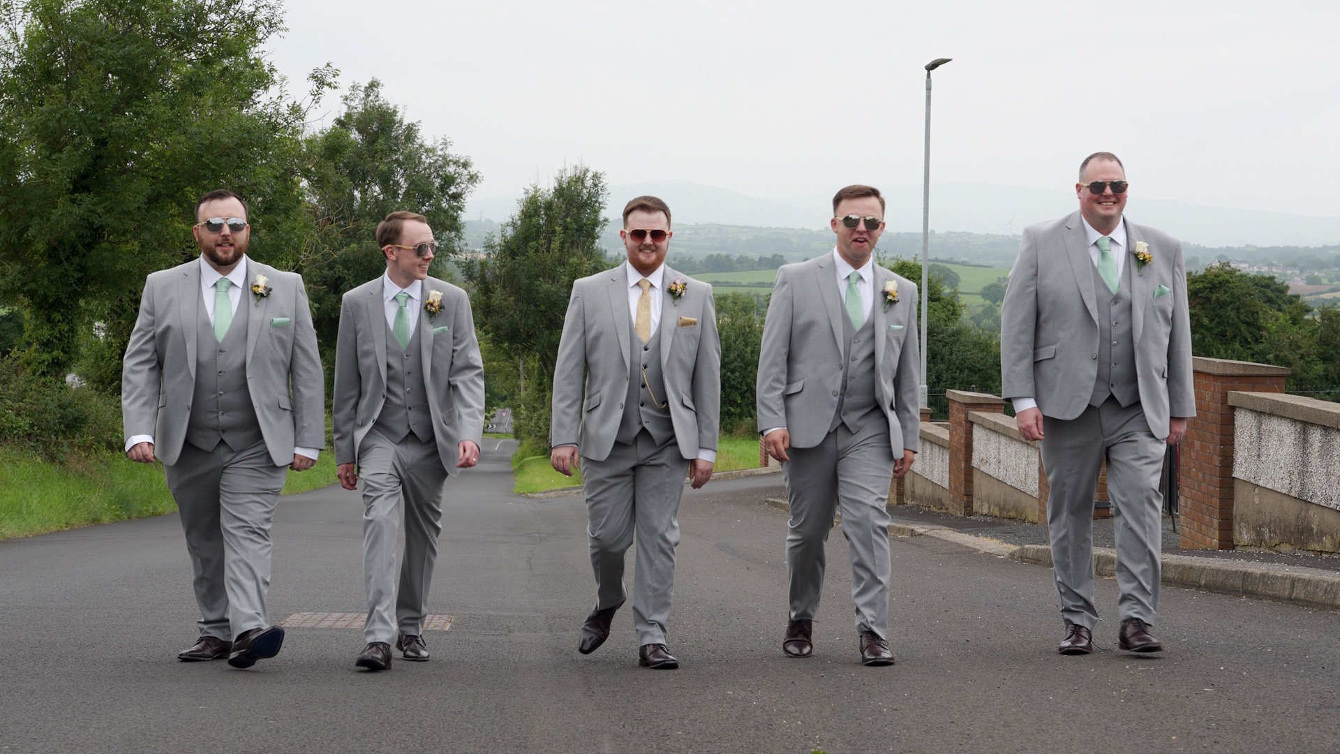 Groom Christopher and his four groomsmen walking down a road in grey suits and sunglasses in Magherafelt.