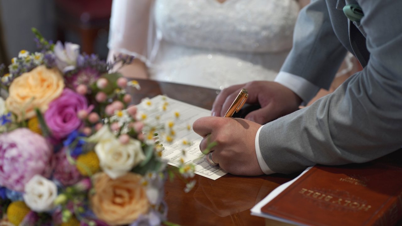 Close-up of signing the marriage register with a gold pen at Calvary Free Presbyterian Church.
