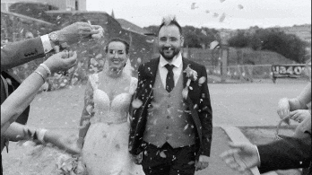 Black and white GIF of Carol-Ann and Sean walking through wedding confetti at Ebrington Square.
