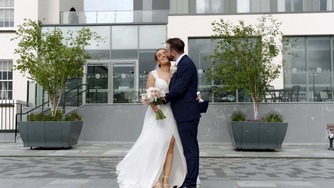 Groom kissing the bride on the cheek outside the Ebrington Hotel in Derry.
