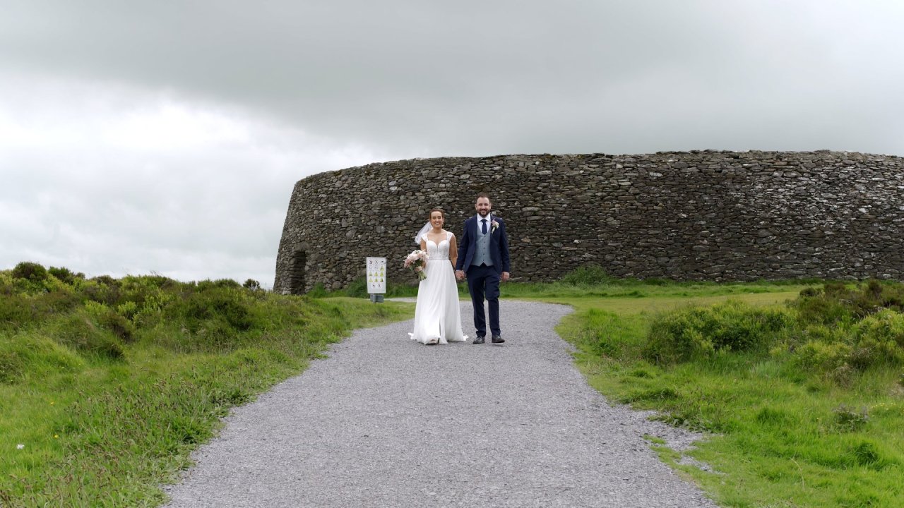 Carol-Ann and Sean walking hand-in-hand along the gravel path at the ancient Grianán of Aileach stone fort.