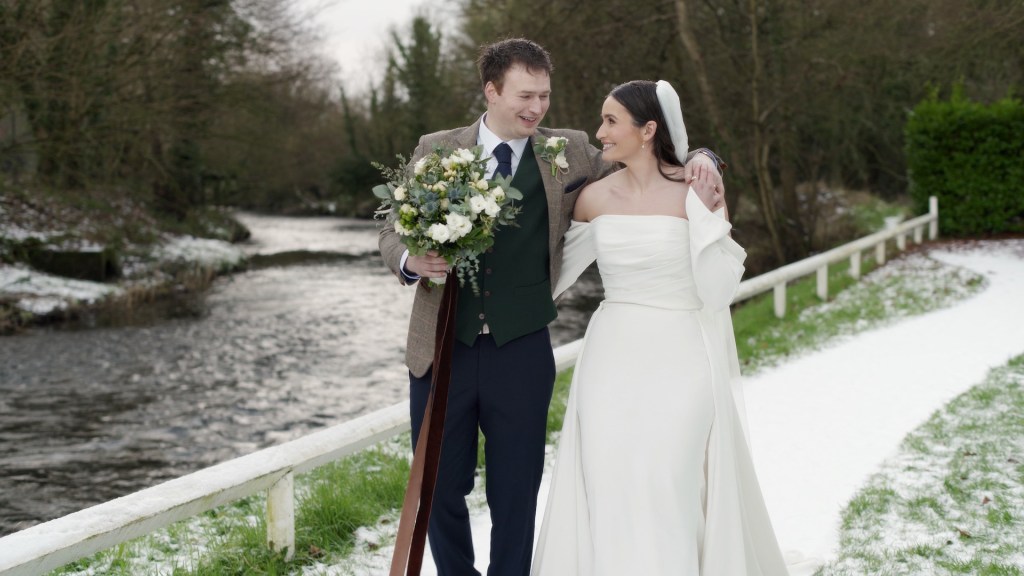 Claire and David walking by the river at Leighinmohr House during golden hour.