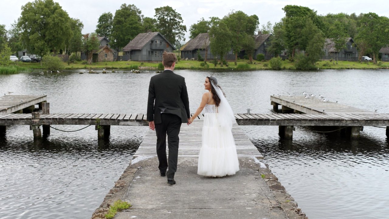 Bride and groom walking hand-in-hand down a pier at Lusty Beg Resort.