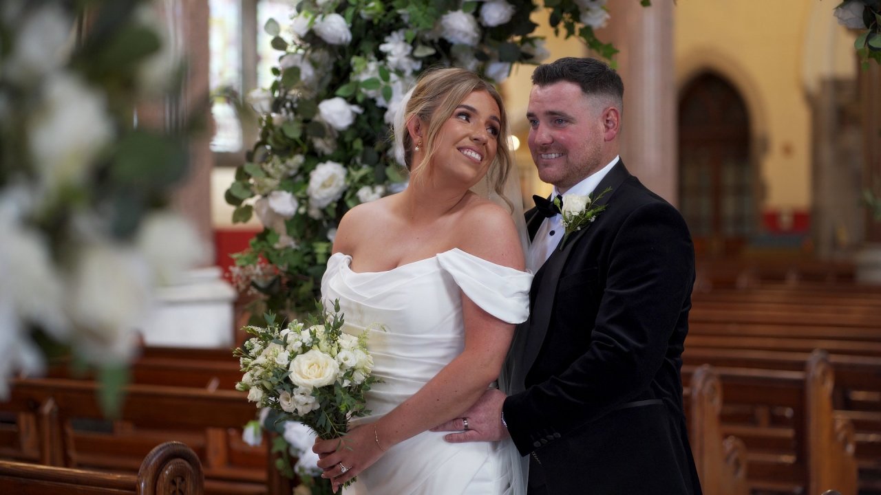 Close-up of Conor holding Cora at the floral arch in Immaculate Conception, Strabane.