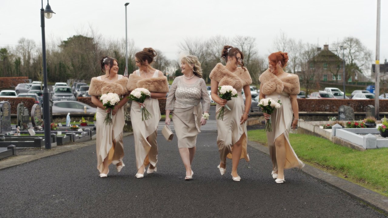 Shannon’s bridesmaids and mother walking together in champagne dresses and fur stoles.