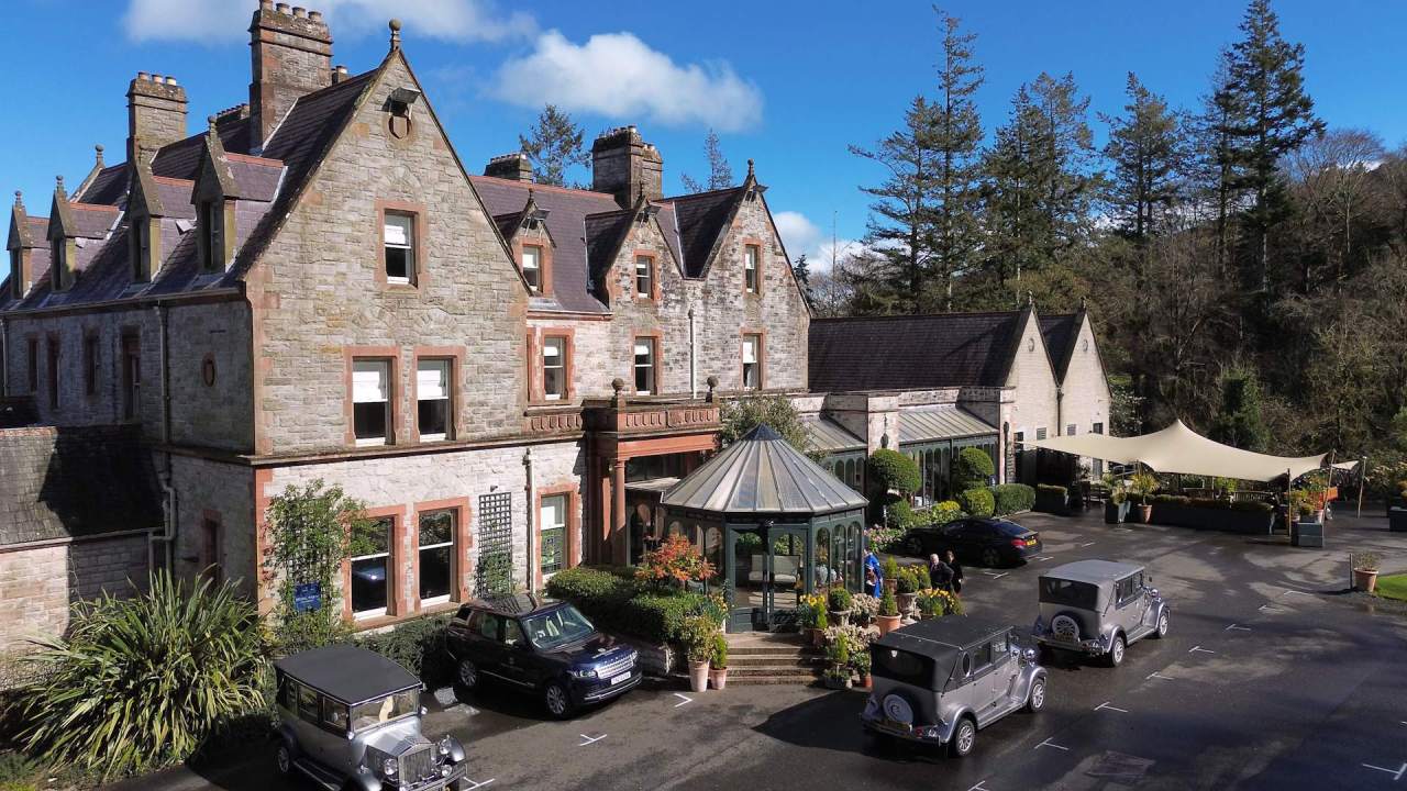 Wide shot of Magheramorne Estate wedding venue in County Antrim with vintage wedding cars.