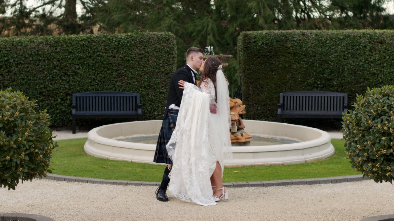 Sam and Amy sharing a kiss in front of the fountain at Magheramorne Estate.