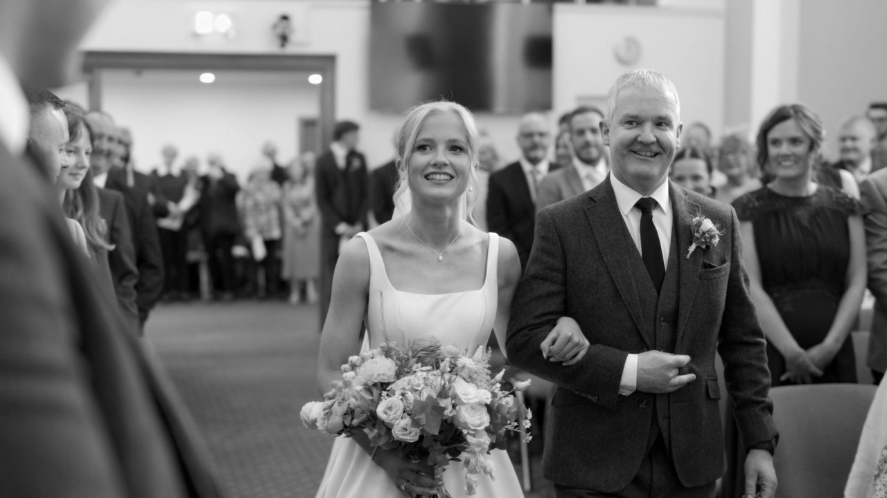 Black and white photo of bride Hannah walking down the aisle at Ballycrochan Baptist Church.