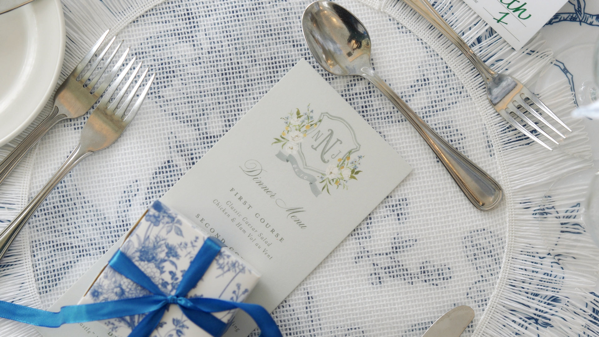 Elegantly set wedding reception table featuring custom menu, blue ribbon gift box, and monogrammed stationeries.