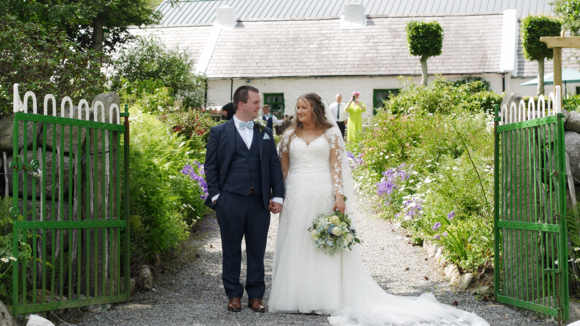 Bride Rebekah and groom Matthew standing together between open green gates at Rocky Mountain Cottage in Hilltown.