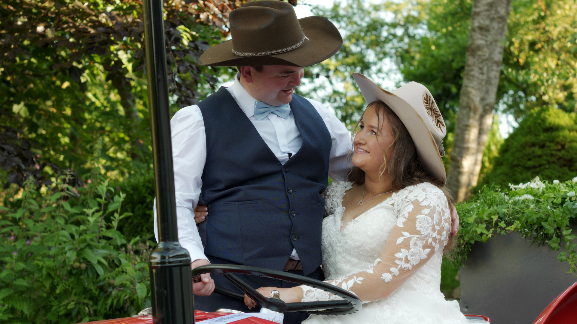 Bride sitting on a vintage red Massey Ferguson tractor with the groom standing alongside at Rocky Mountain Cottage.