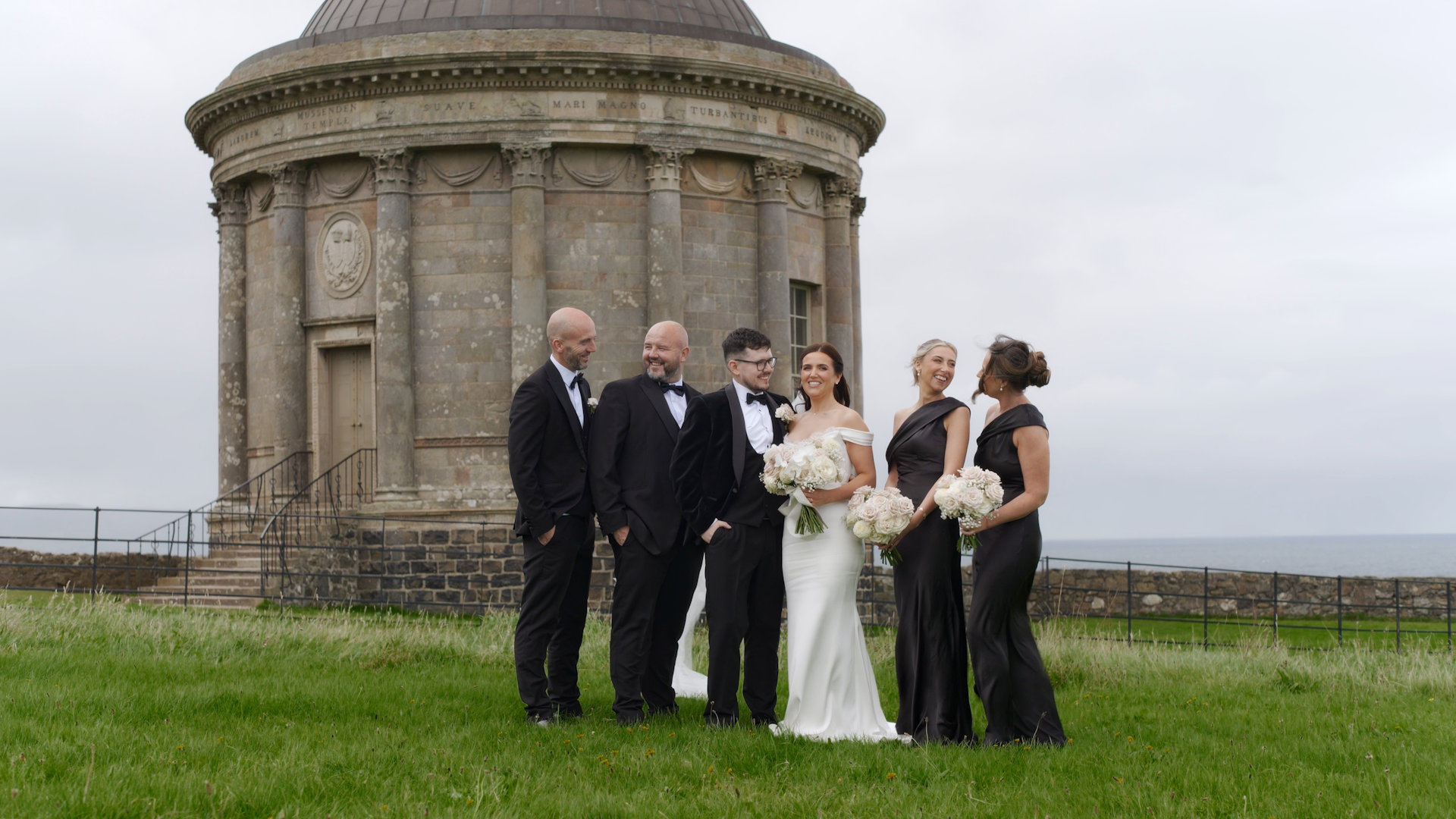 Wedding party laughing outside Mussenden Temple on the North Coast of Northern Ireland.