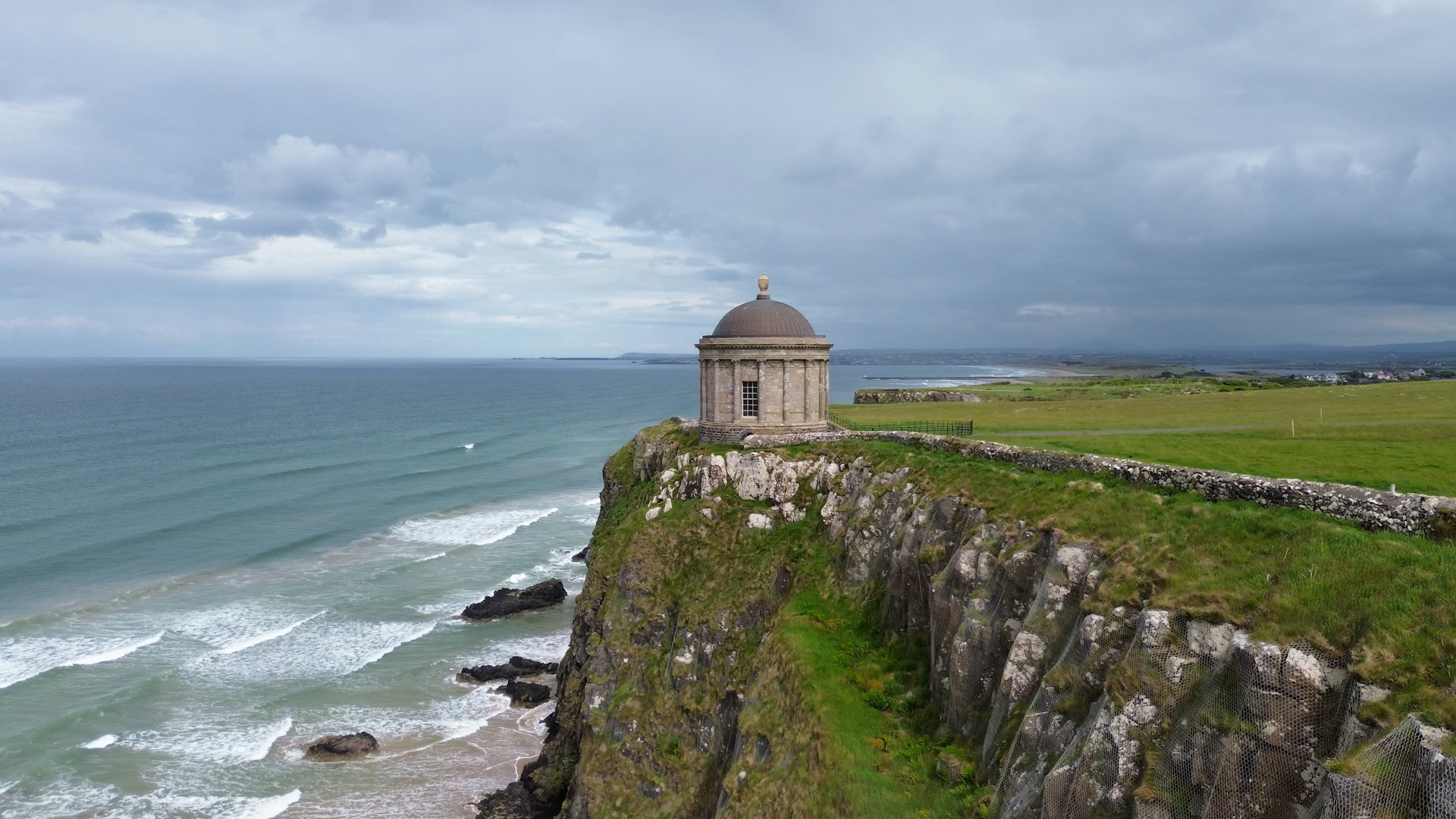 Aerial drone shot of Mussenden Temple perched on the ocean cliffs above Downhill Strand.